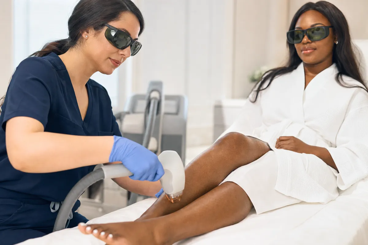 A clinician performing a professional diode laser treatment on an adult patient's lower leg